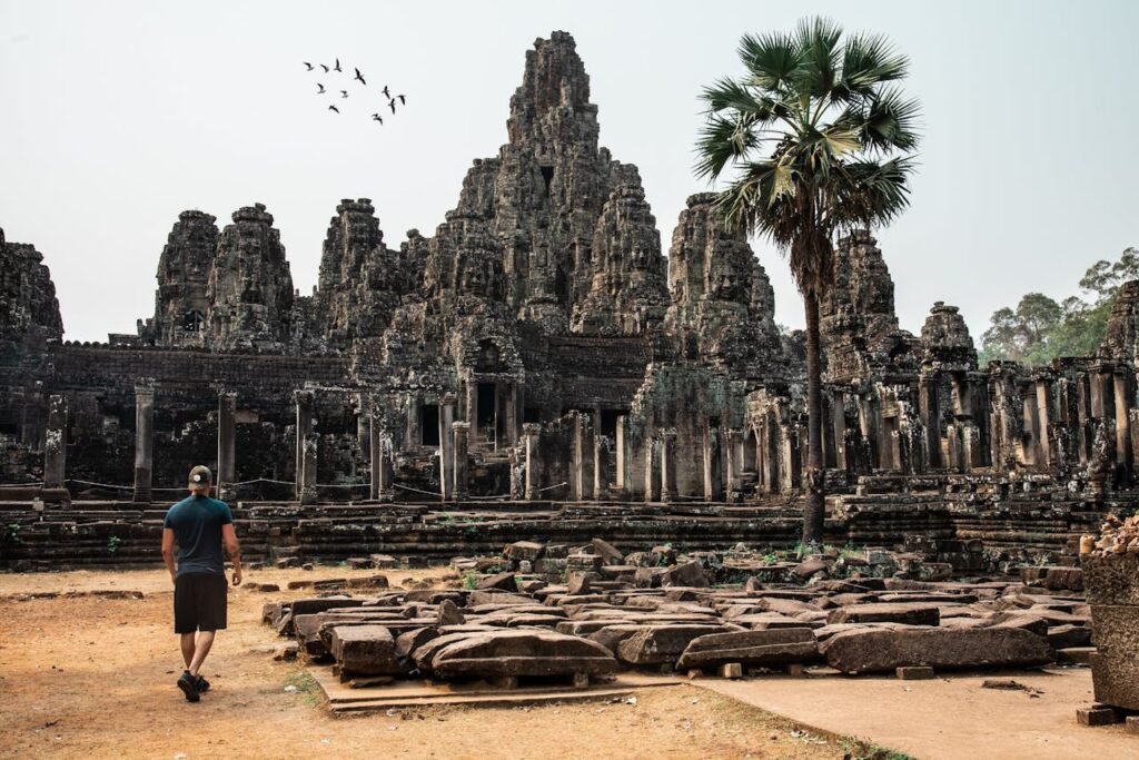 Mastering the First Impression: Your intriguing post title goes here Traveler exploring the ancient Bayon Temple at Angkor Thom, Cambodia, surrounded by stunning architecture.